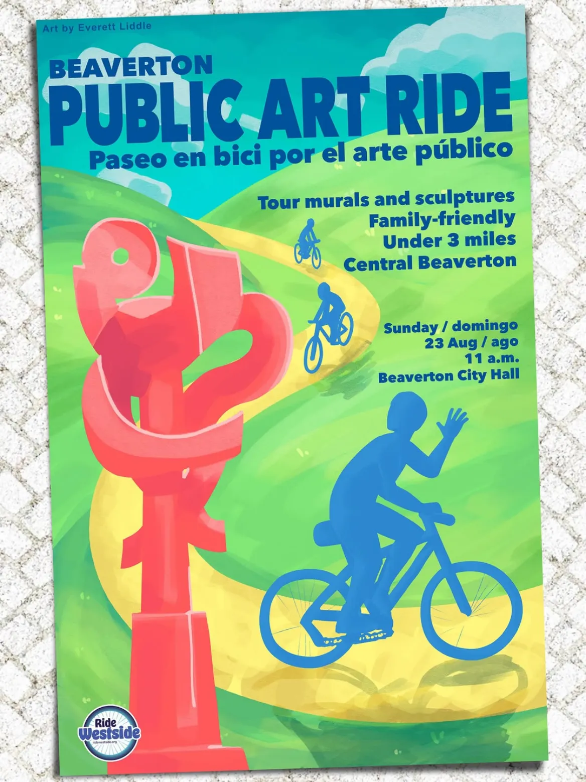 Photograph of the printed Beaverton Public Art Ride poster mounted on a pale stucco wall, its design in a flat travel poster style: a coral red abstract sculpture stands at the left against rolling green hills and a yellow path curving back toward a teal sky, with small blue silhouetted cyclists on the path and a waving rider in the foreground, the bilingual title set in heavy blue sans-serif above the ride details.